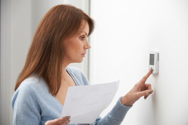 Woman adjusting thermostat